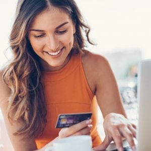 Smiling woman with credit card and laptop