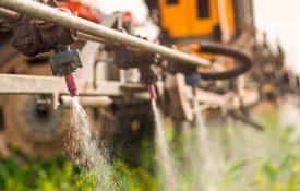 Crop sprayer spraying pesticides on crops in field