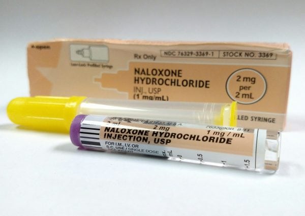 Prescription box for Naloxone Hydrochloride, opioid antagonist, with a pre-filled syringe of the naloxone HCL lying in front of the box.