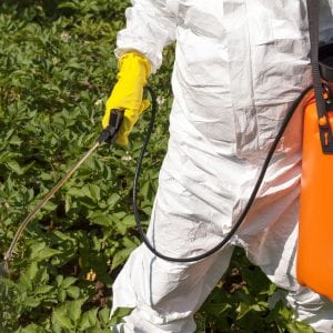 person wearing protective clothing while spraying pesticides