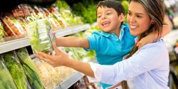 A hispanic mother and her son in the produce section of a grocery store.