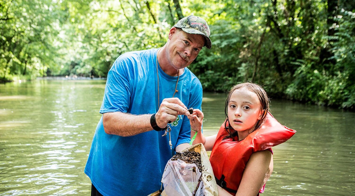 Alabama 4-H volunteer and member in creek during lesson