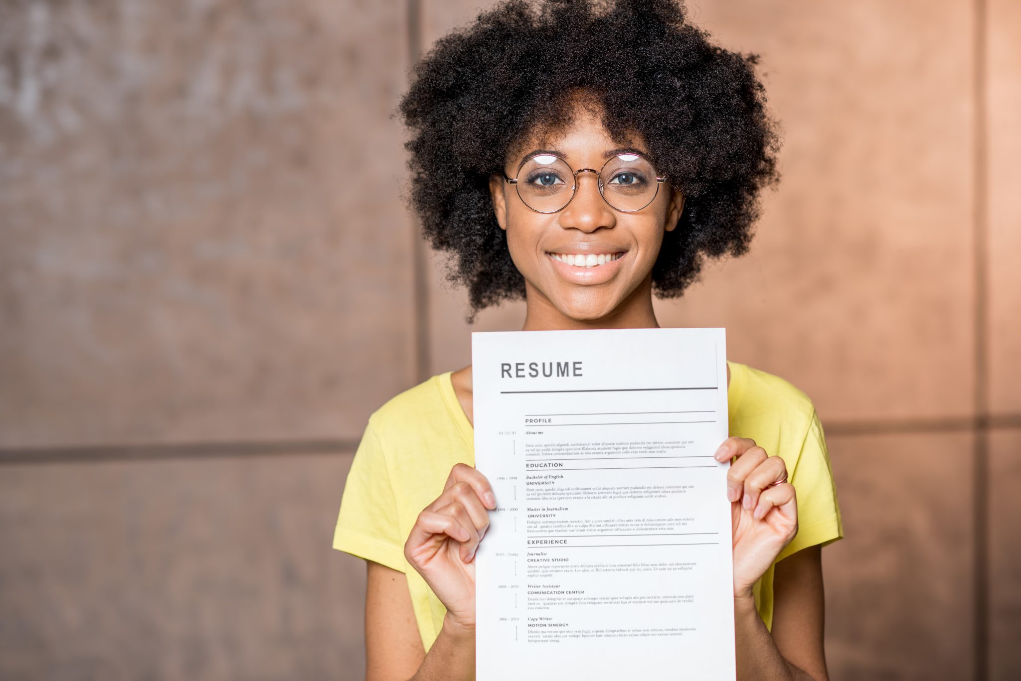 Portrait of a young African woman holding resume document indoors