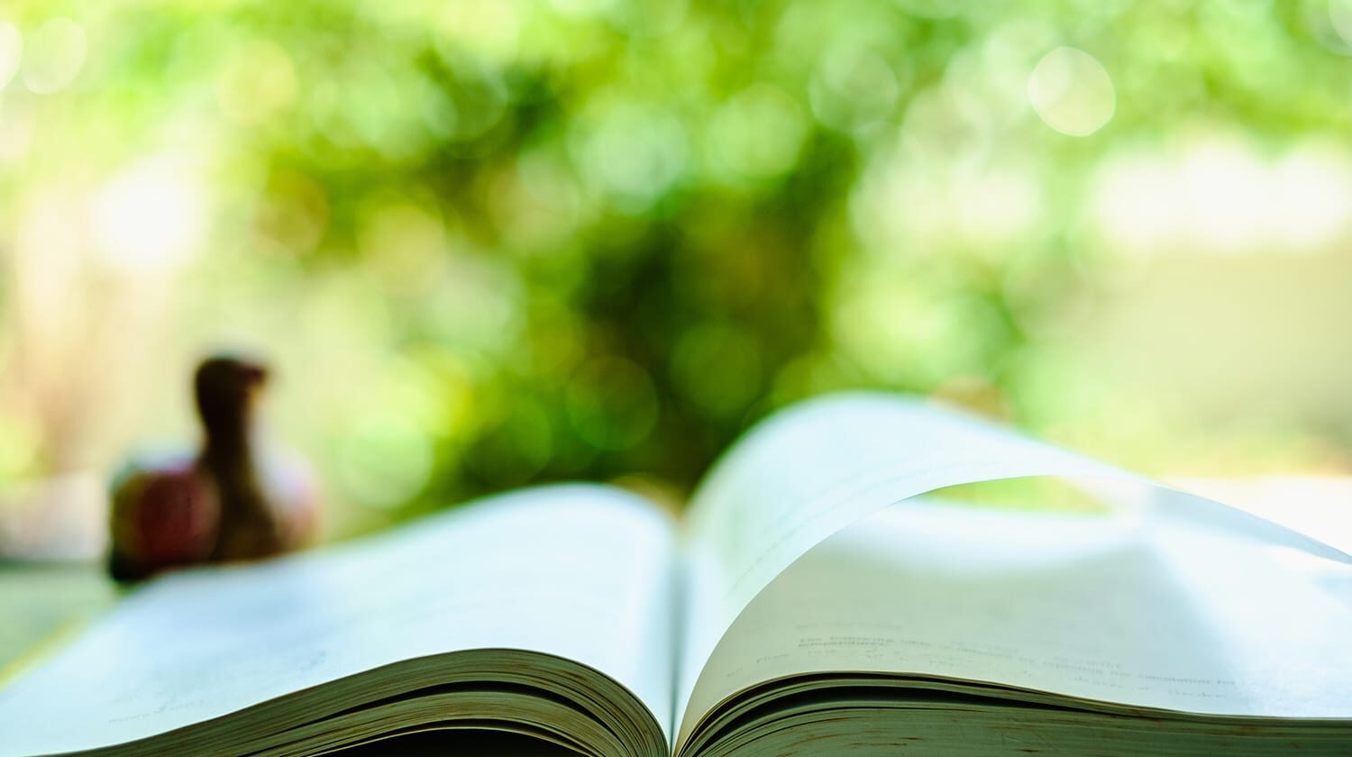 An open book open on a table in an outdoor setting.