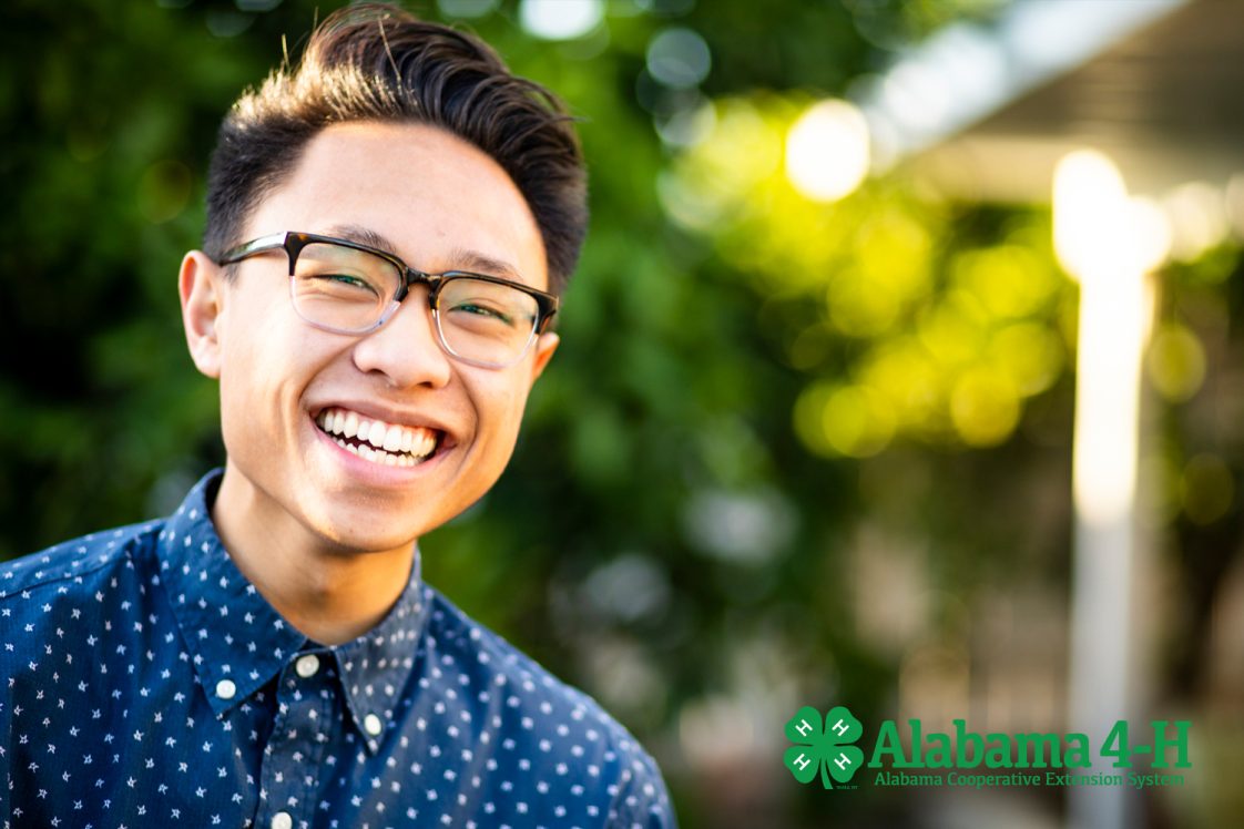 Smiling Asian male student with reading glasses.