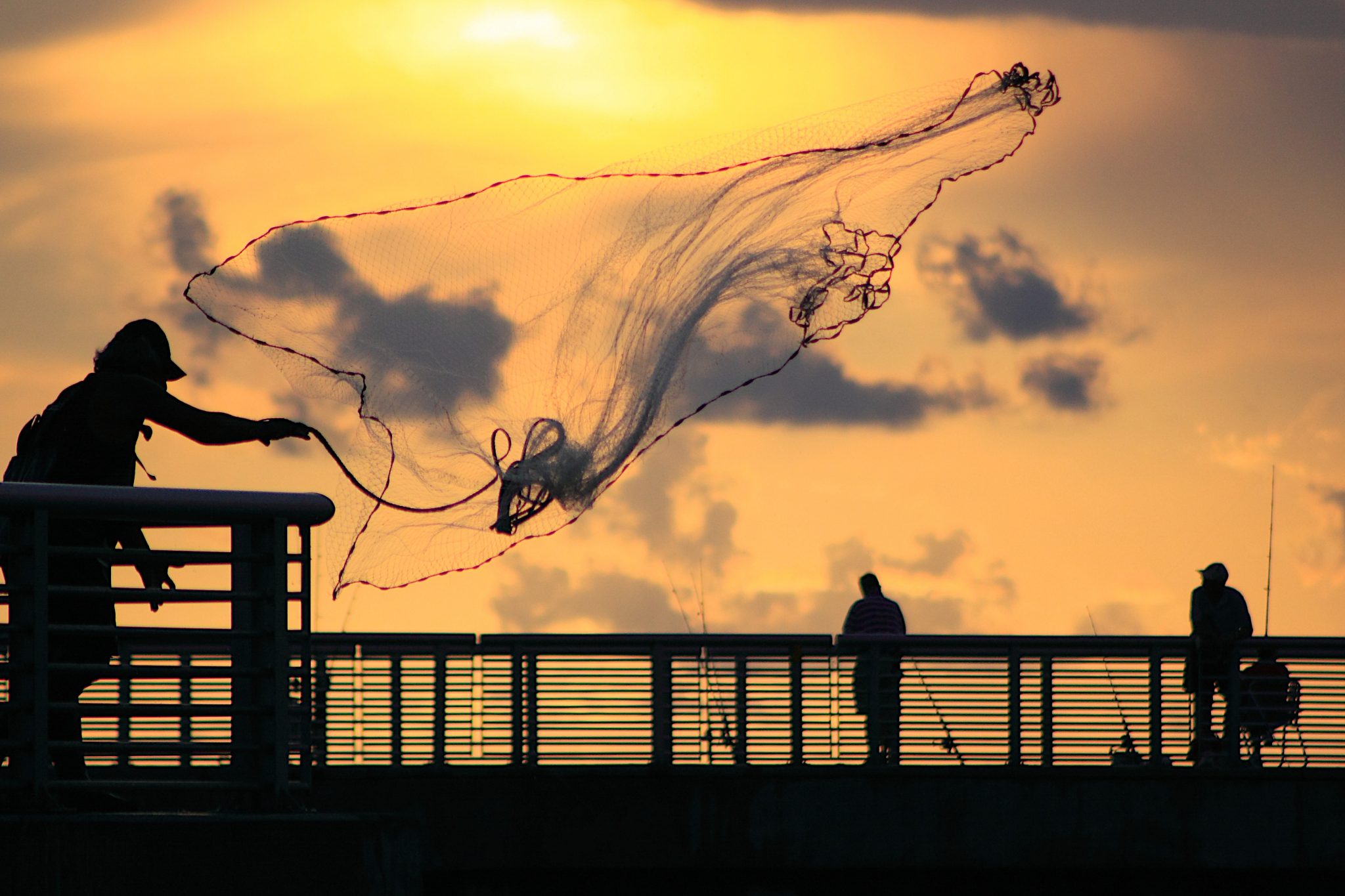 Fisherman casting a net during sunrise