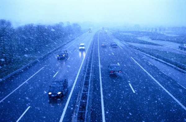 high angle view of traffic driving on a freeway in snowfall