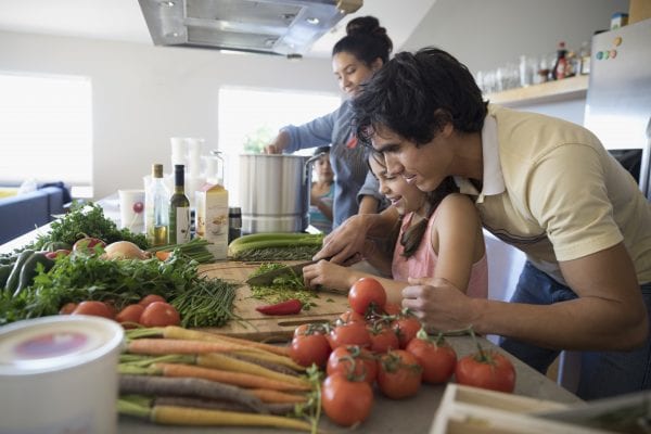 Family cooking, cutting vegetables in kitchen