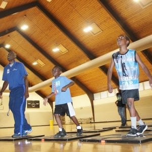 A group of school-age children are in a church gym exercising with the TEEN exergame.