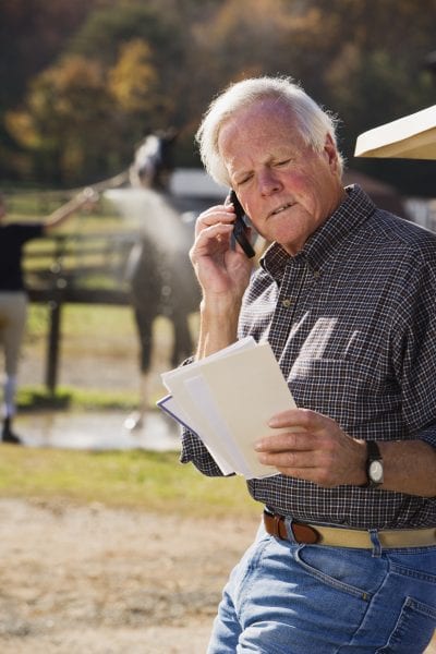 Farmer with paperwork on cell phone