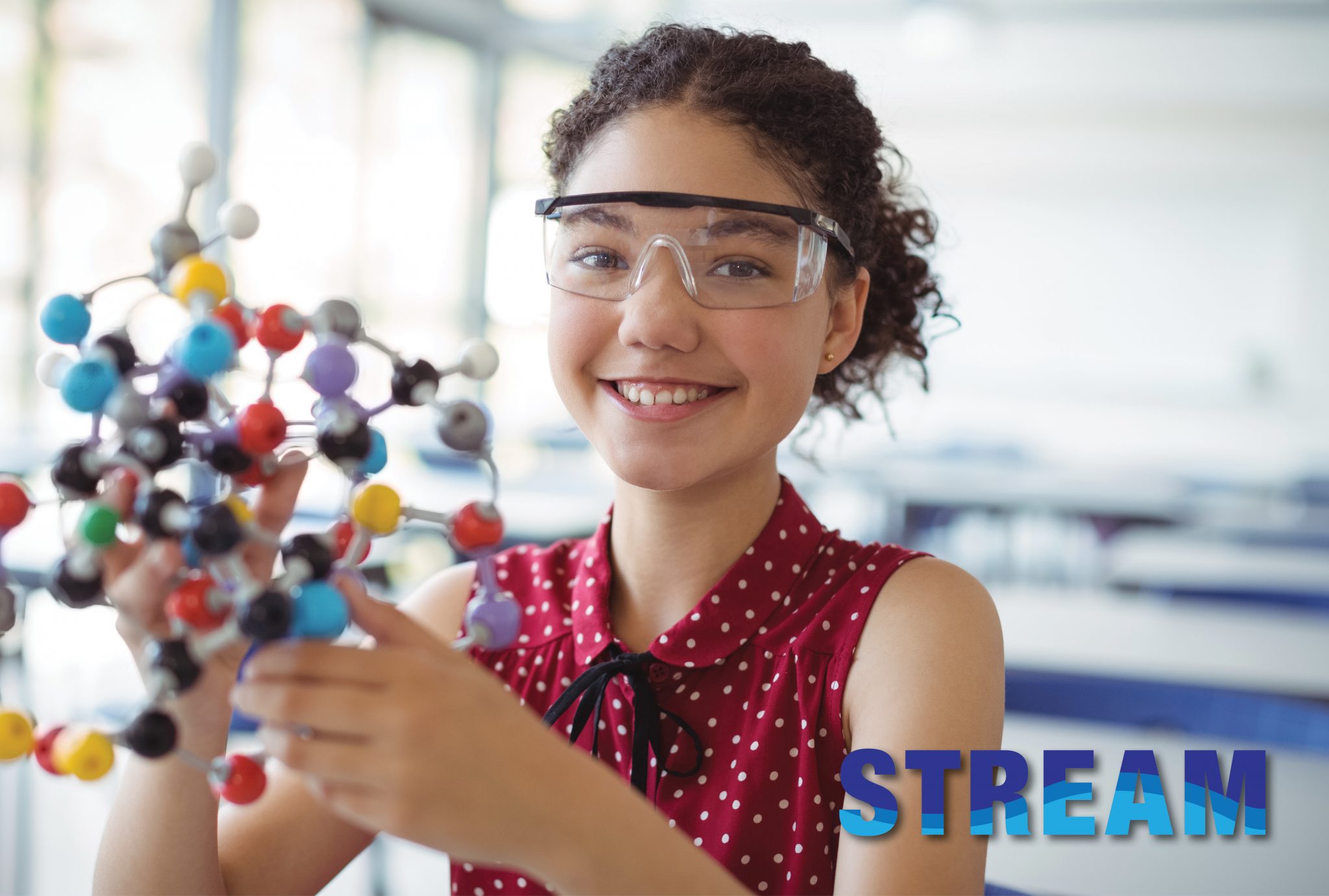 Middle school aged girl holds a scientific model while wearing safety glasses.