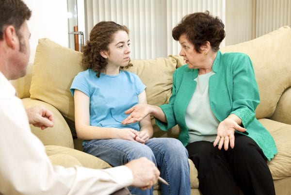 Teenage girl and her mother meeting in a family therapist's office for counseling.