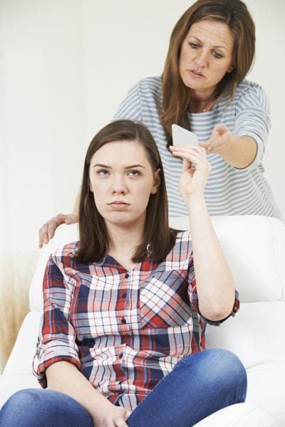 Mother Taking Mobile Phone Away From Teenage Daughter