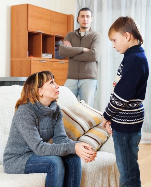 Mother and father scolding teenager son at living room