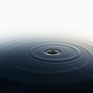 Drop of water rippling in still pool