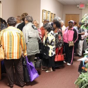 A large group of older adults file into the conference auditorium