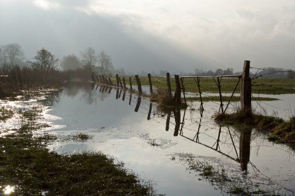 A flooded pasture with a fence line. 