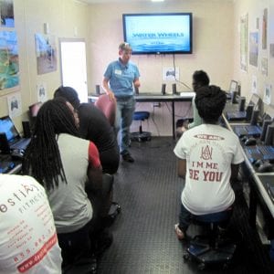 Participants are sitting inside the Waterwheels mobile laboratory listening to instruction before using gaming computers