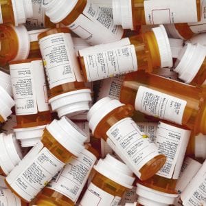 Dozens of prescription medicine bottles in a jumble. This collection of pill bottles is symbolic of the many medications senior adults and chronically ill people take.