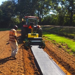 Figure 2. This tractor-drawn mulch layer implement lays the plastic and drip tape into beds while anchoring the edges with soil.