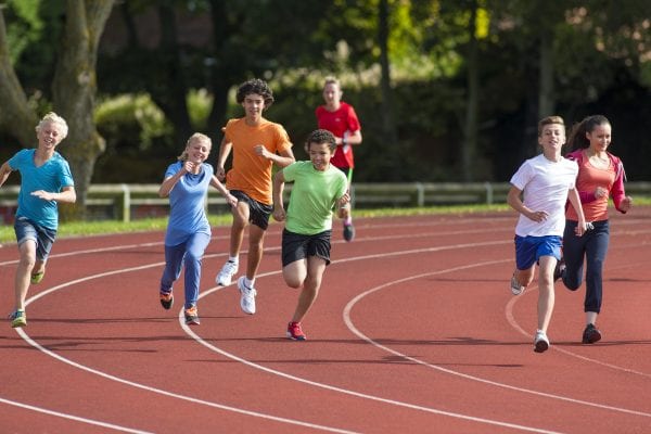 Panning shot of a group of teenagers running a track race.