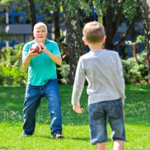 Grandfather Playing American Football Game With Kid In The Park