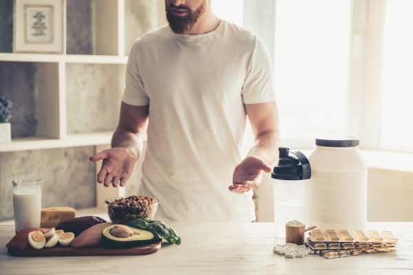 Cropped image of handsome young sportsman preparing sport nutrition in kitchen at home