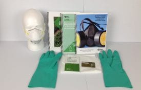 Image of training manuals, green gloves, face mask and other documents.