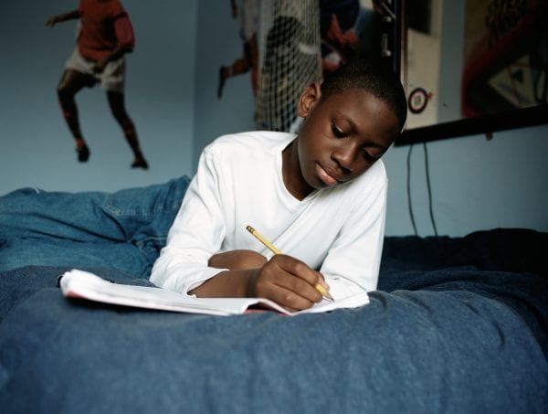 Boy doing homework on bed