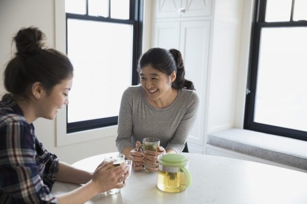 Mother and teenage daughter drinking tea and talking