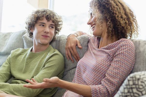 Happy mother and son talking on couch in living room