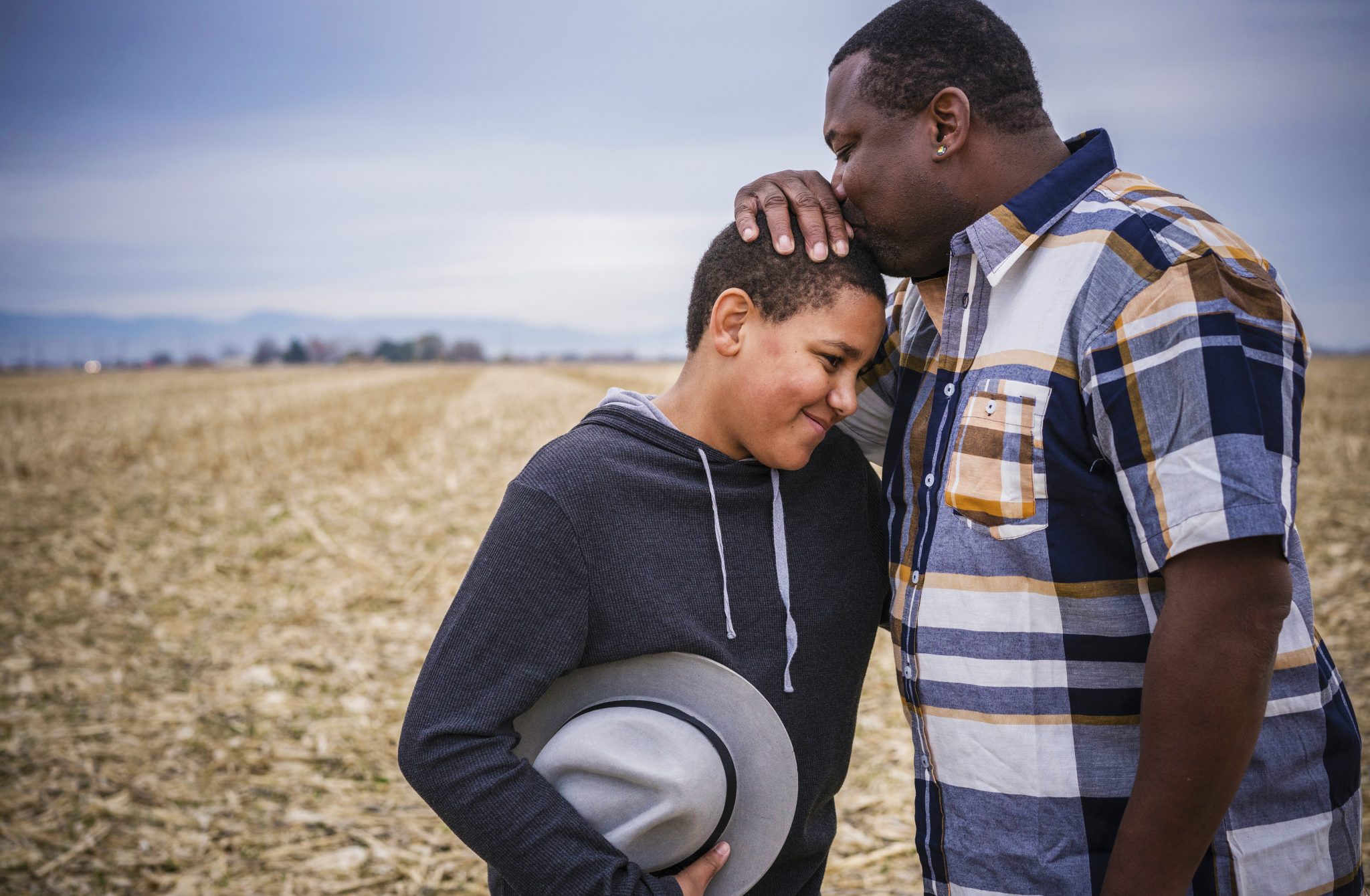 Father kissing son on head in field