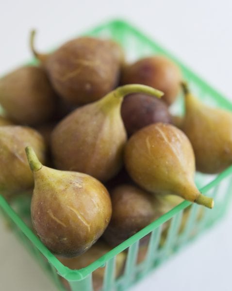 Figs sitting in a green produce basket