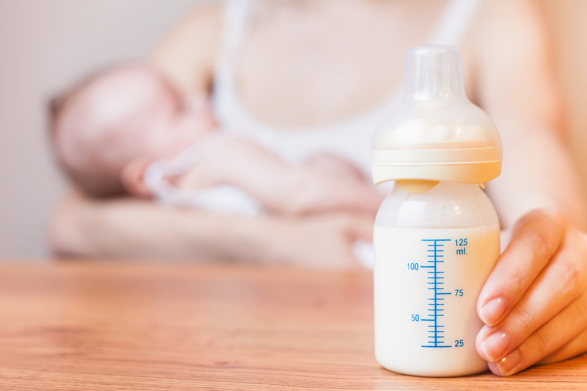 Mother breastfeed ing baby with bottle in the foreground