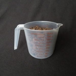 A plastic measuring cup filled with bark.