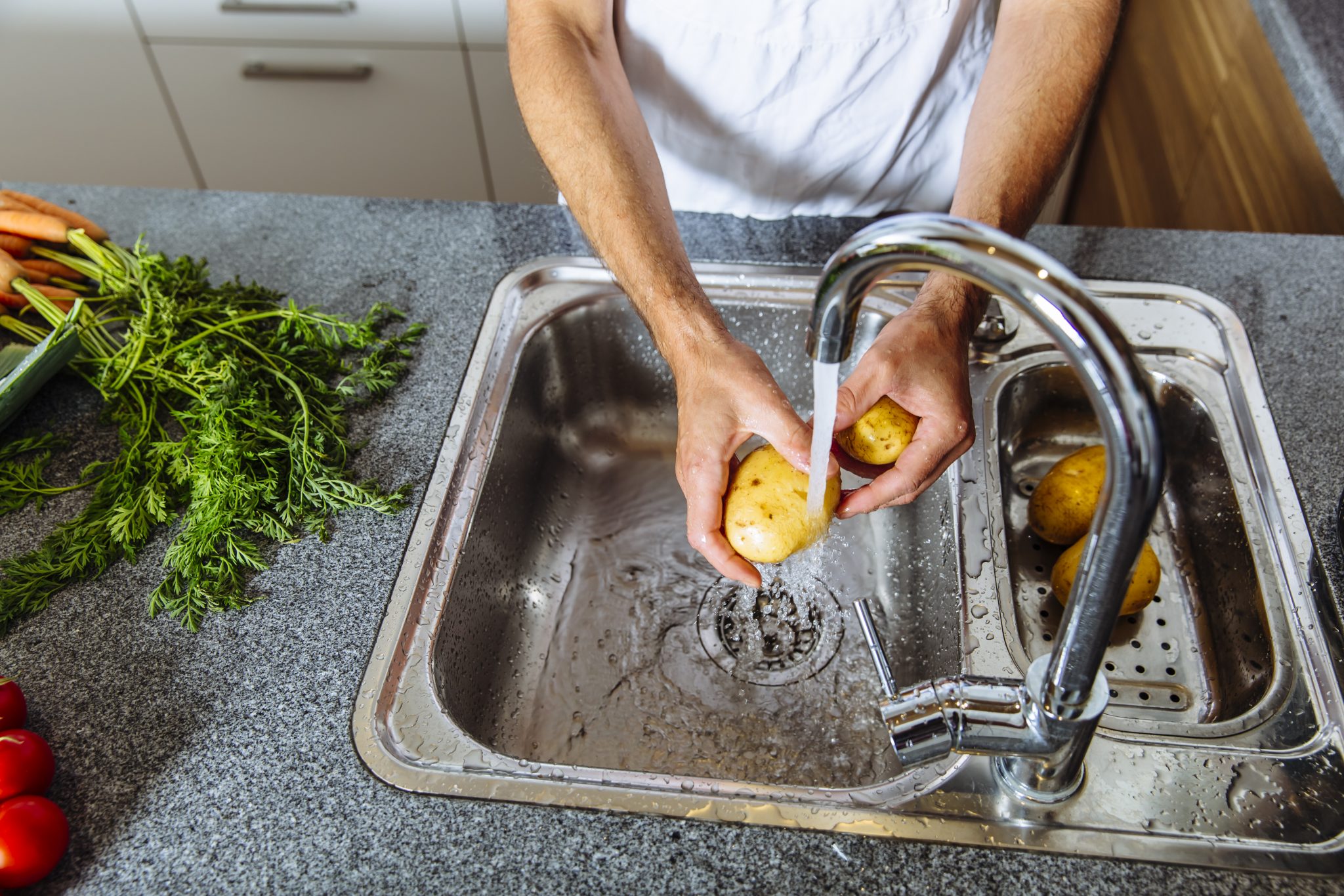 man washing vegetables in modern kitchen