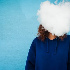 Young woman with her head in a cloud of vapor smoke
