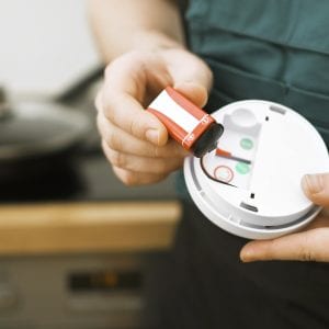 Man checking battery in smoke detector in the kitchen.
