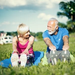 Senior couple stretching together outdoors.