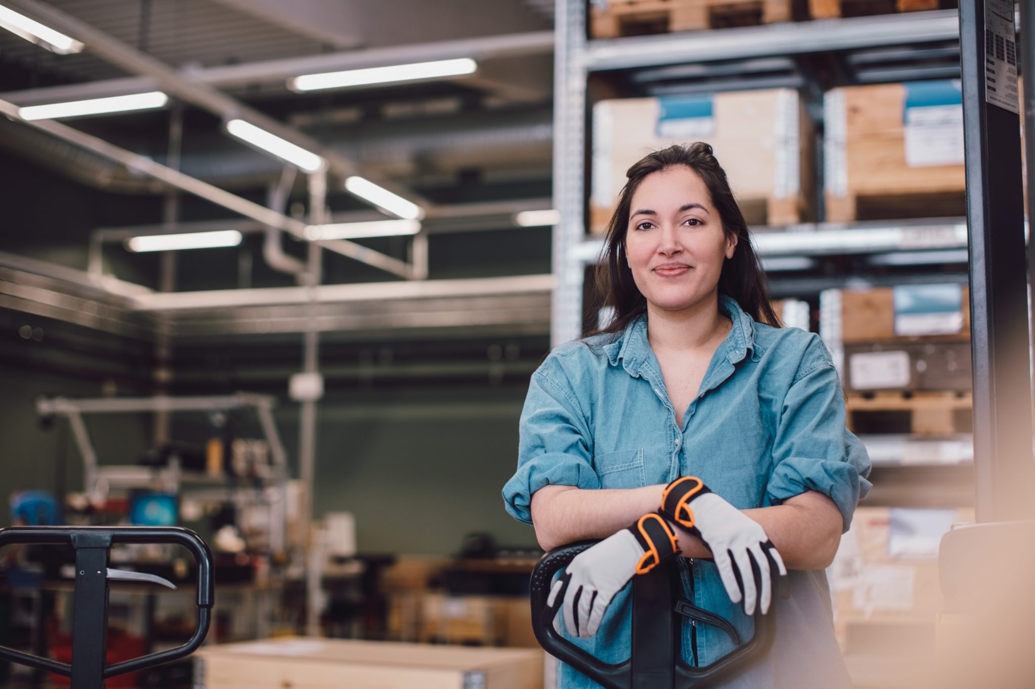 Portrait of young worker leaning on pallet jack at warehouse