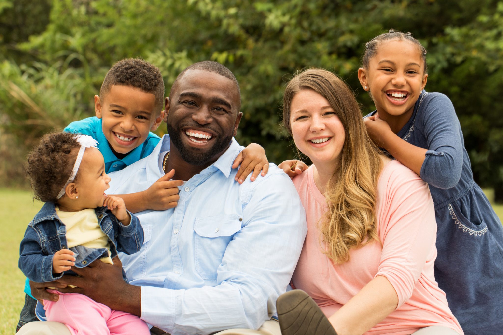 An interracial family smiling outdoors