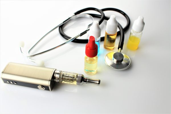 Close-Up Of Electronic Cigarette And Stethoscope On Table