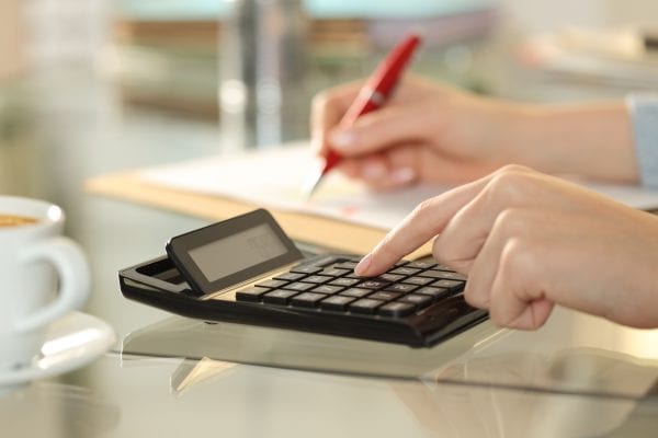 Woman hands using calculator and writing on a desk