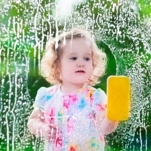 Little girl washing a window