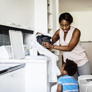 Black kid helping mom doing the laundry