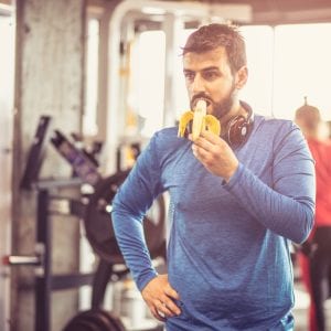 While man eating a banana at the gym