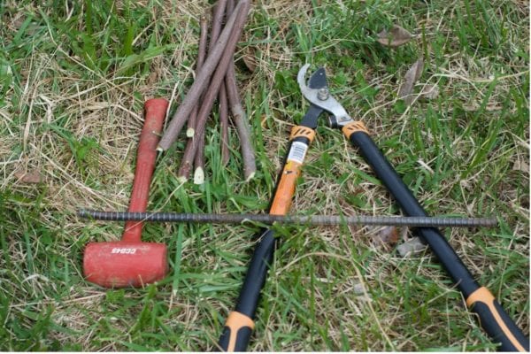 sledge hammer, iron rebar, pruning shears, and stakes made from tree limb sections