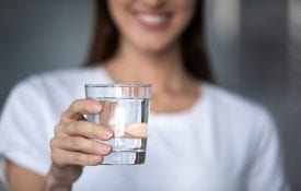 Smiling young lady holding a glass of water