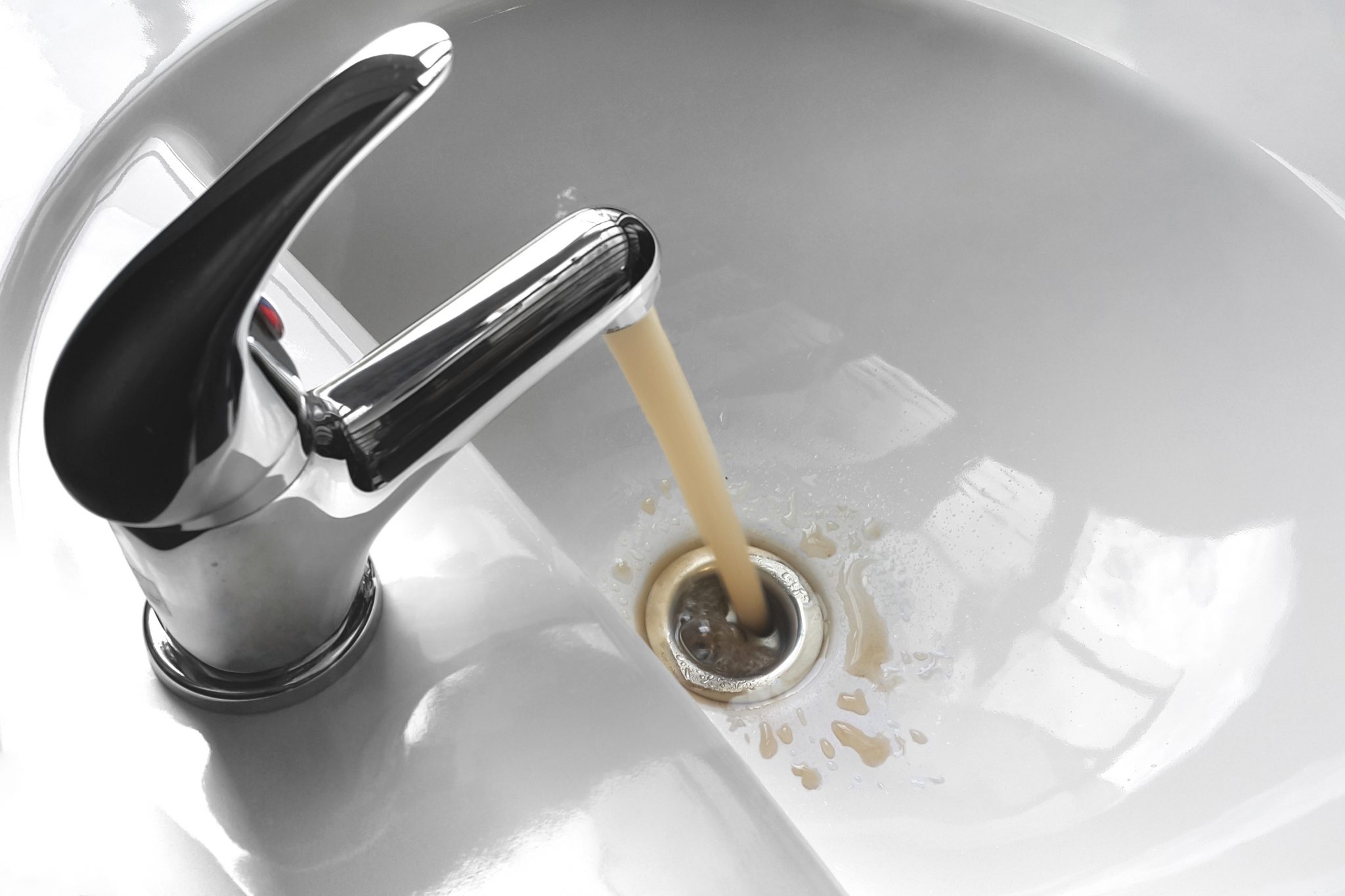 A faucet running with brown water