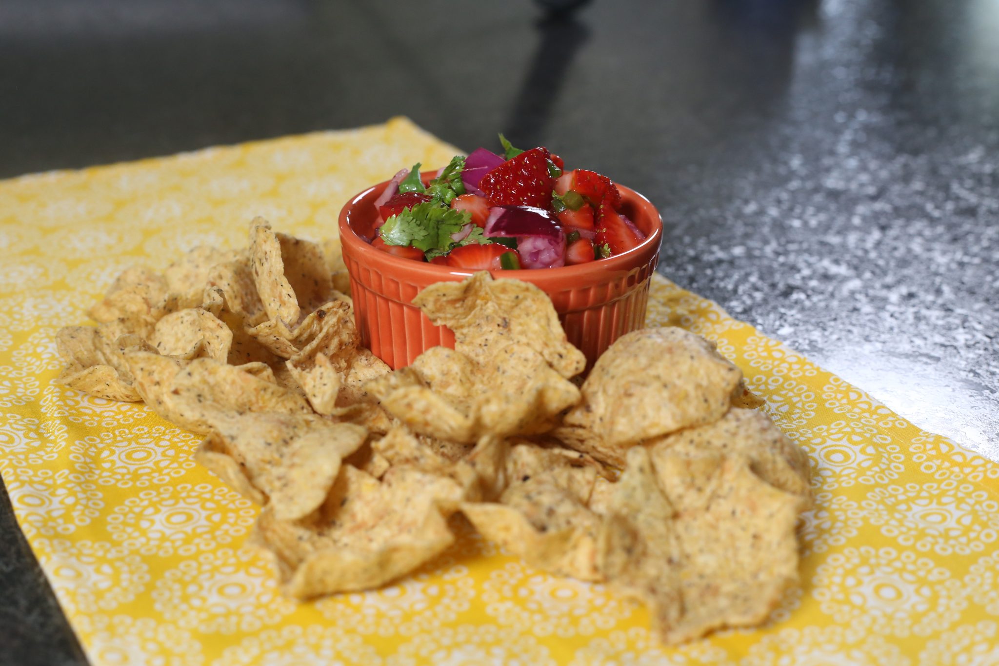 salsa, chips, brown cutting board